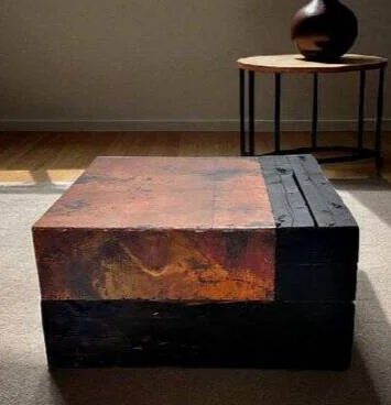 Square coffee table of stacked blackened timber and a hammered copper block top