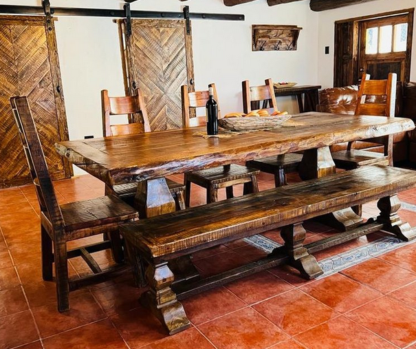 Rustic live-edge dining table with trestle bench and ladder-back chairs on terracotta tile