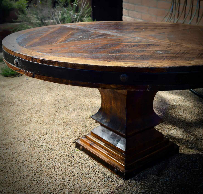 Round reclaimed wood dining table with a star-pattern top, iron band and a stepped pedestal base
